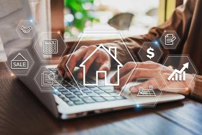 Hands typing on a laptop surrounded by real estate and home ownership icons